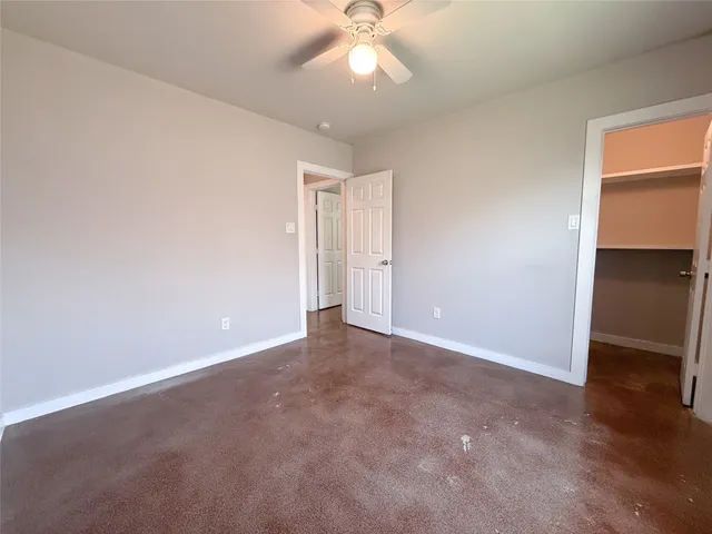 an empty room with closet and a chandelier fan