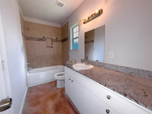 a bathroom with a granite countertop sink a toilet a mirror and bathtub