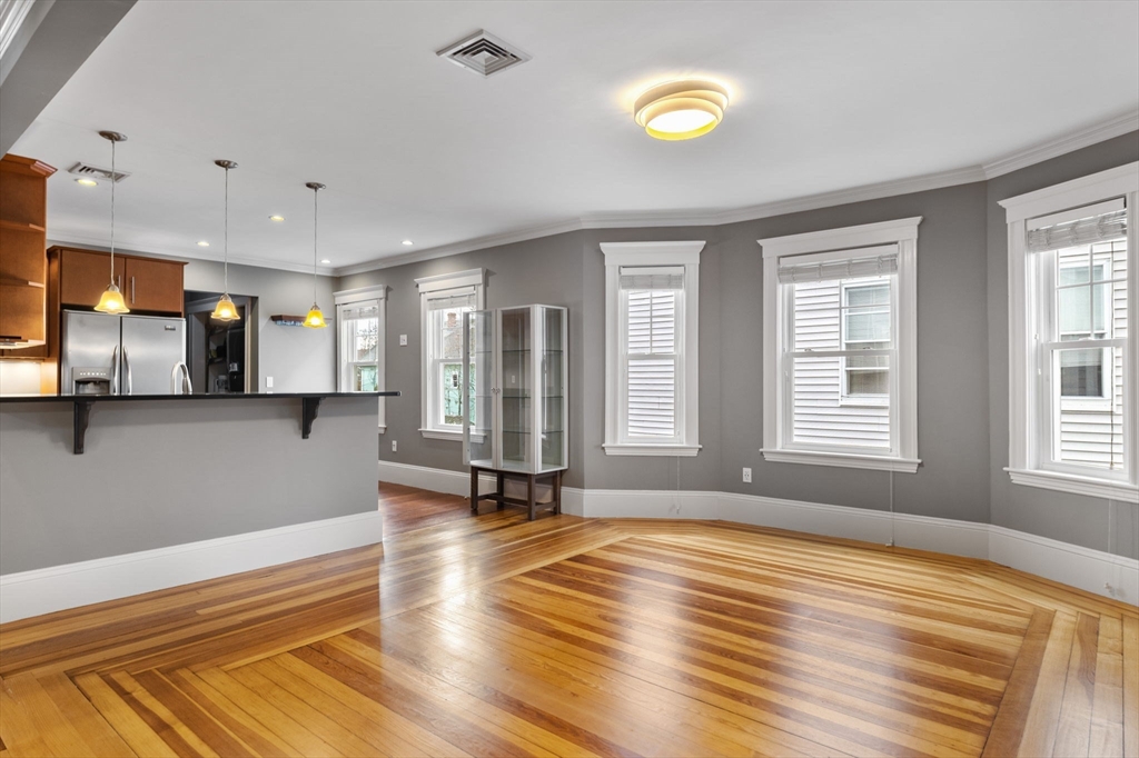 a view of an empty room with window and wooden floor