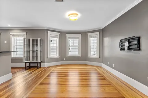 a view of an empty room with window and wooden floor