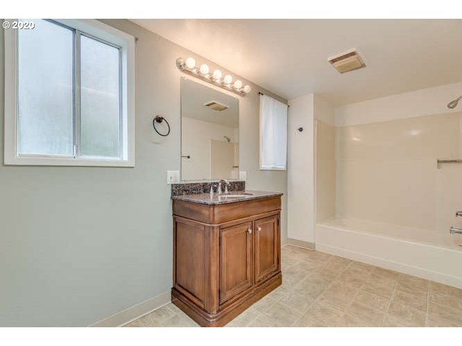 481 South Pine Street Canby, OR 97013 - Photo 9 of 17 a bathroom with a granite countertop sink a mirror and a shower