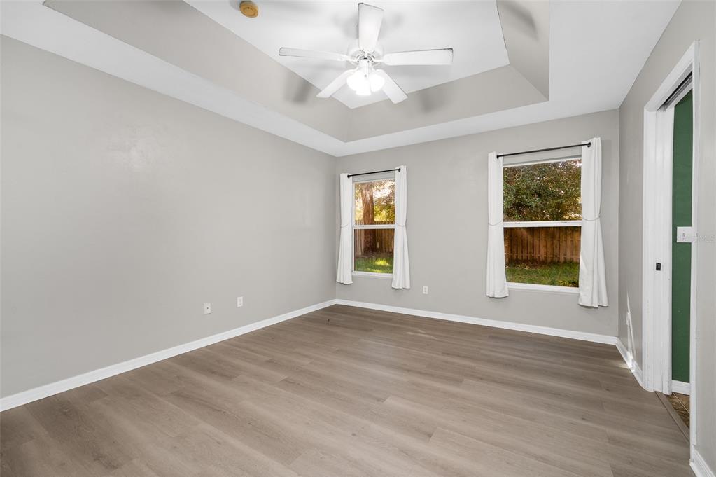 7462 Southwest 84th Drive Gainesville, FL 32608 - Photo 13 of 42 an empty room with wooden floor chandelier fan and windows