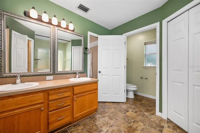 a bathroom with a double vanity sink mirror and toilet