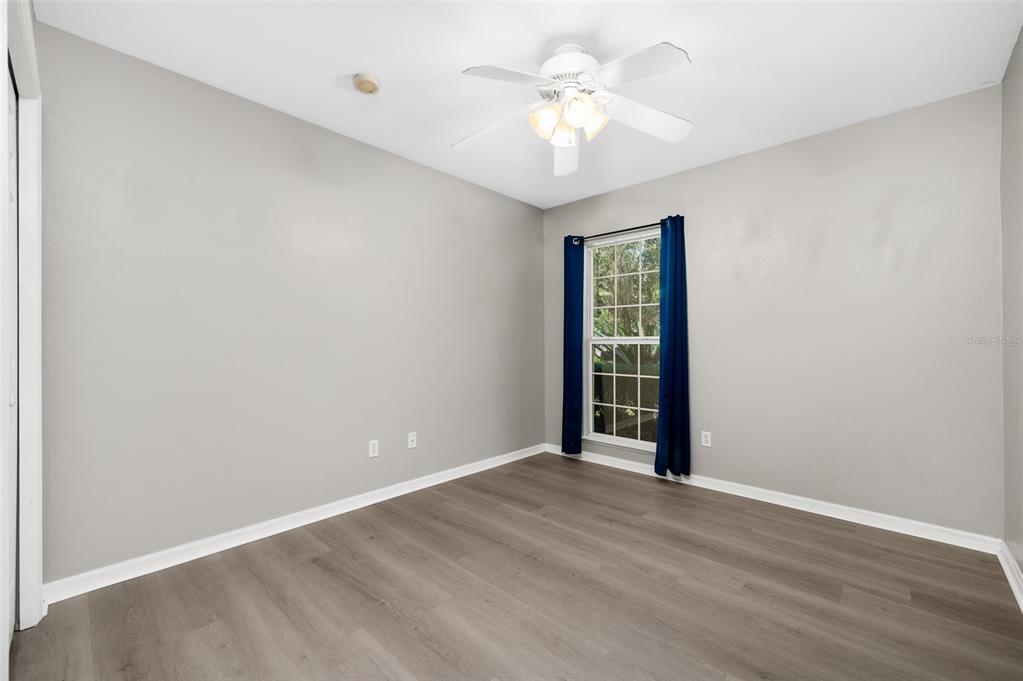 7462 Southwest 84th Drive Gainesville, FL 32608 - Photo 23 of 42 an empty room with wooden floor chandelier fan and windows