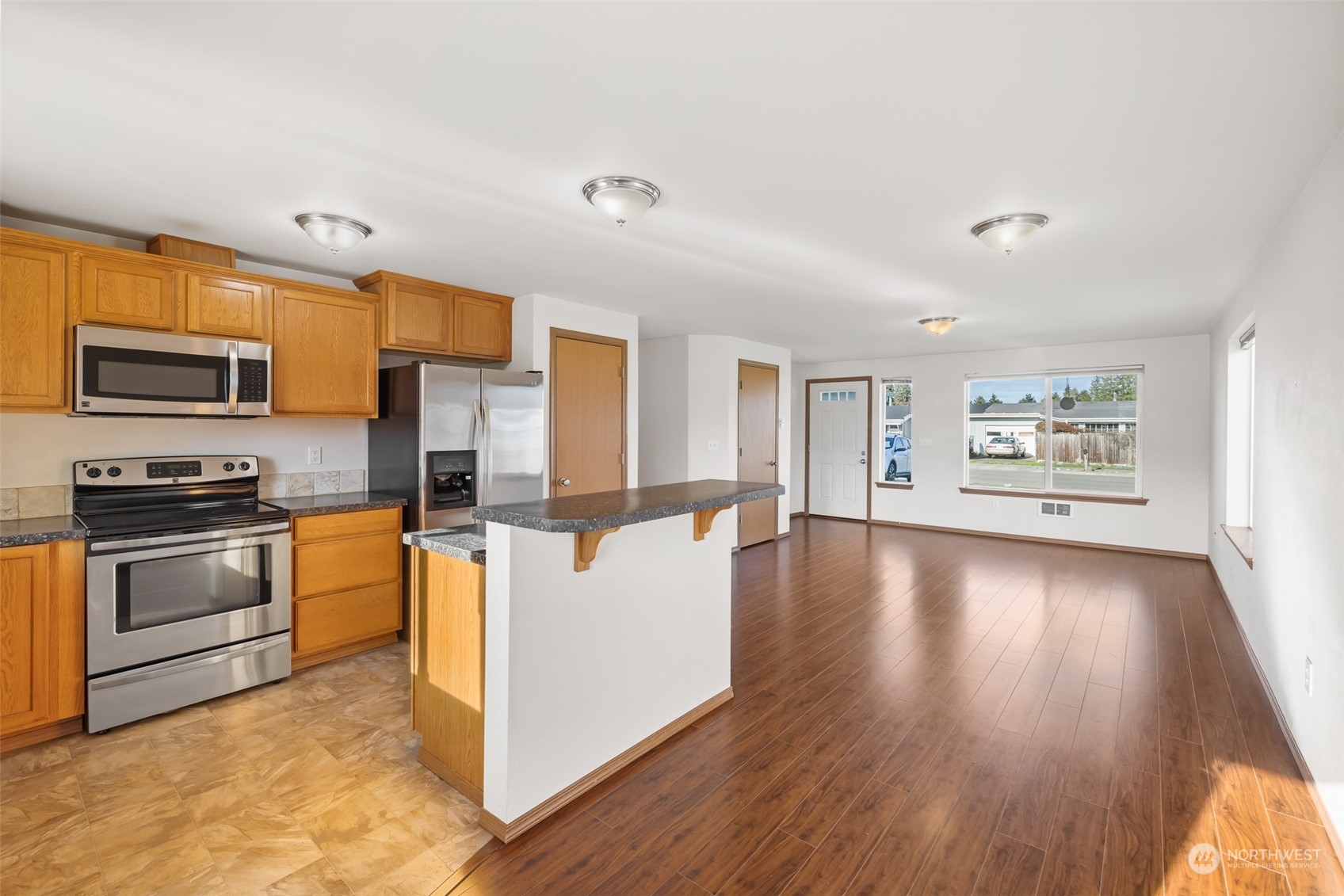 709 East Fir Street Sequim, WA 98382 - Photo 10 of 29 a kitchen with stainless steel appliances a stove top oven a sink dishwasher and a refrigerator with wooden floor