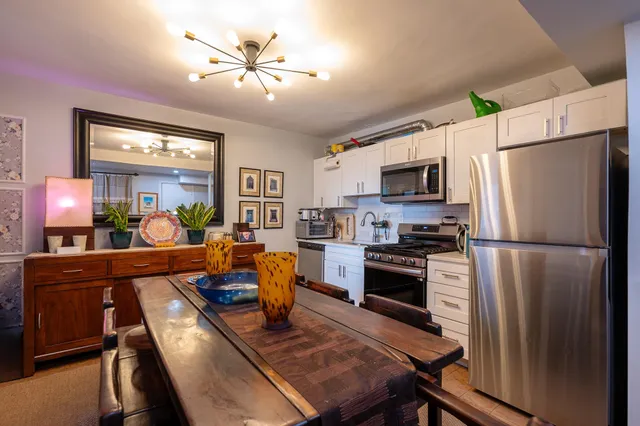 a kitchen with stainless steel appliances a stove a refrigerator a sink a dining table and chairs with wooden floor