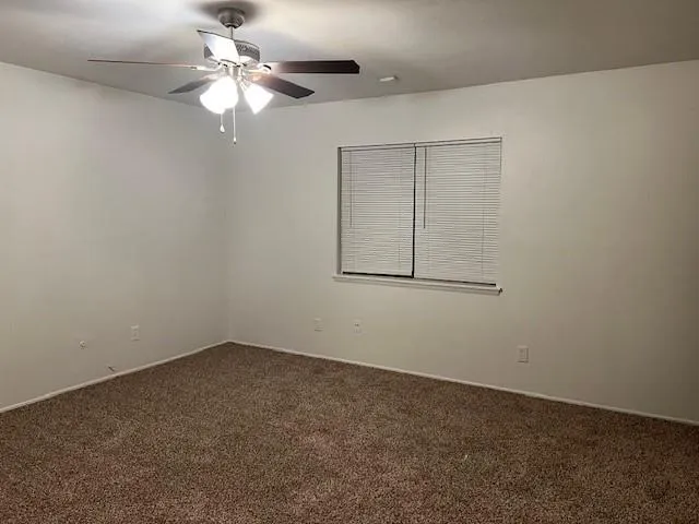 an empty room with a chandelier fan and windows