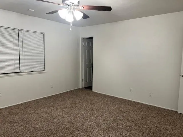 an empty room with a chandelier fan and windows