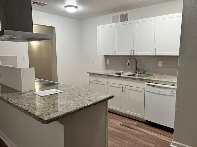 a kitchen with granite countertop a sink a stove and cabinets
