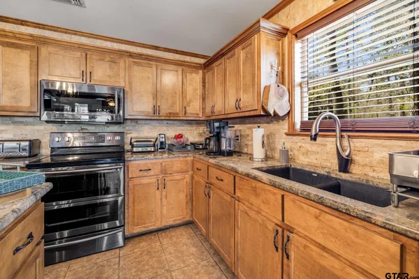a kitchen with stainless steel appliances granite countertop a sink a stove and cabinets
