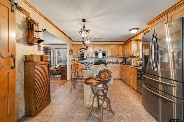 a kitchen with stainless steel appliances kitchen island granite countertop dining table chair and a refrigerator