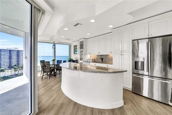 a kitchen with stainless steel appliances granite countertop a refrigerator a sink a stove and a wooden floors