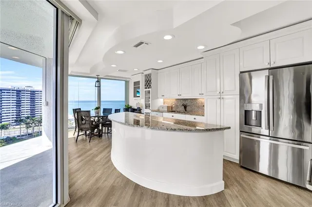 a kitchen with stainless steel appliances granite countertop a refrigerator a sink a stove and a wooden floors