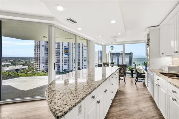 a large kitchen with stainless steel appliances granite countertop a large counter top a stove and a wooden floors