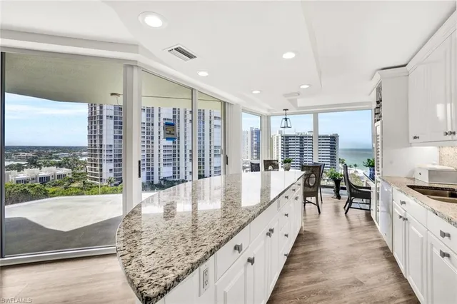 a large kitchen with stainless steel appliances granite countertop a large counter top a stove and a wooden floors