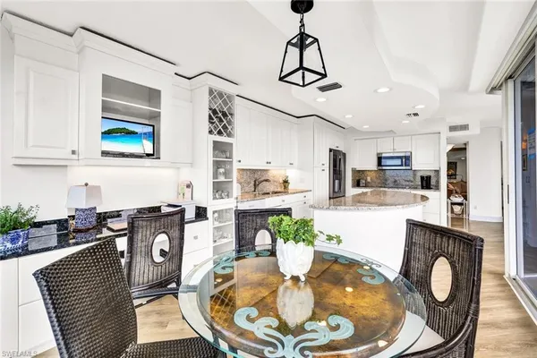 a kitchen with stainless steel appliances granite countertop a dining table chairs and chandelier