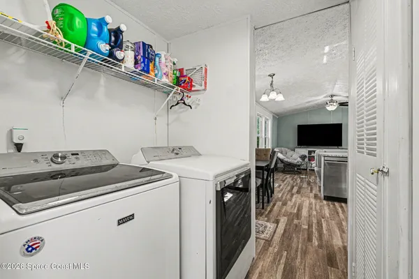 a utility room with dryer washer and a view of living room