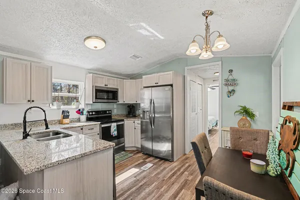 a kitchen with granite countertop stainless steel appliances a sink stove and refrigerator