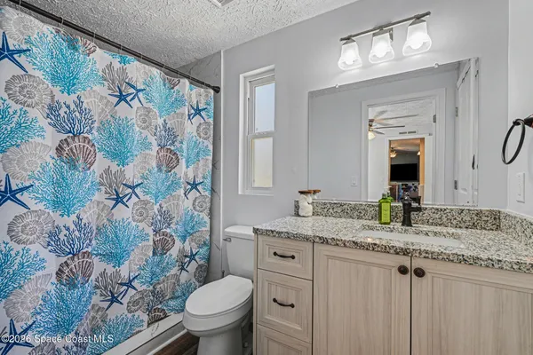 a bathroom with a granite countertop sink a toilet and a mirror