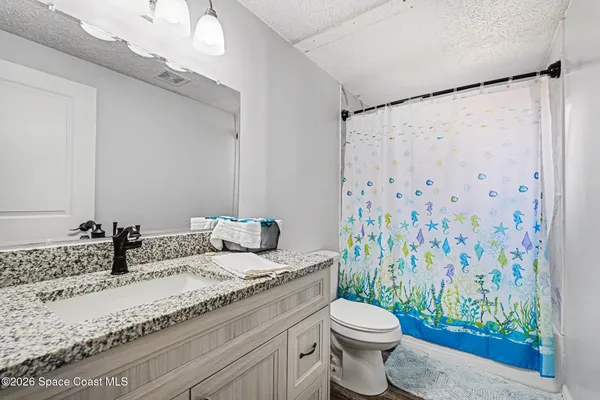 a bathroom with a granite countertop sink a toilet and a shower curtain