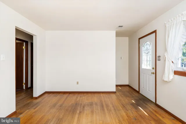 an empty room with wooden floor and entrance