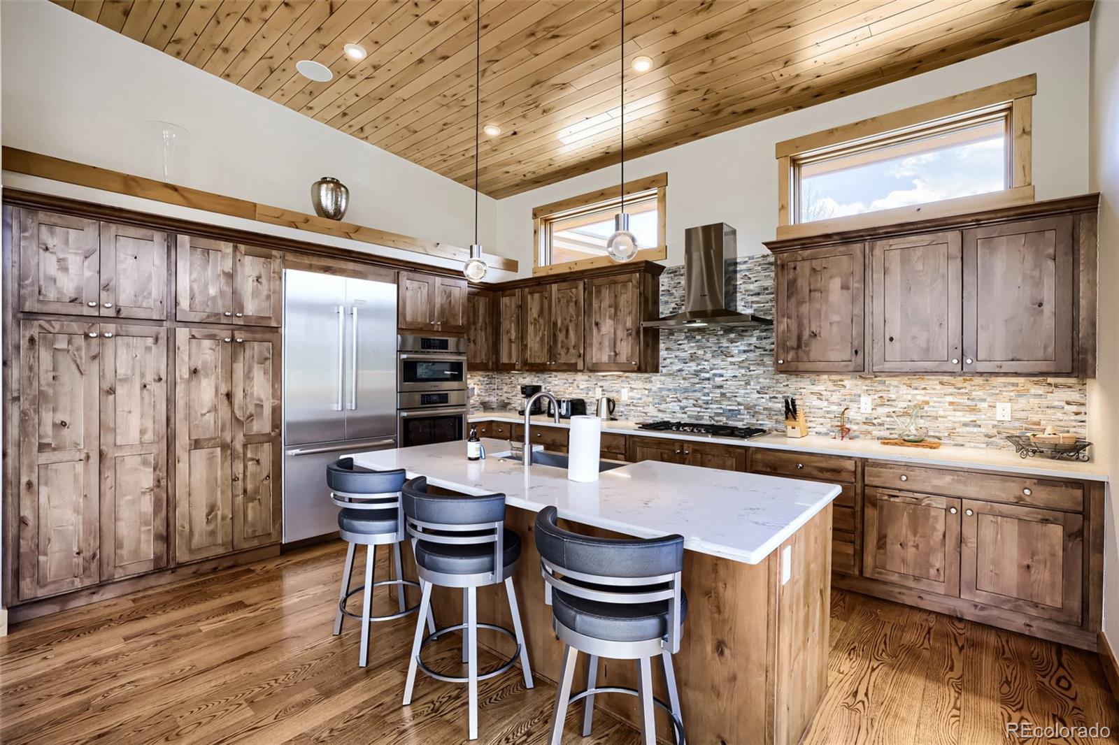 836 Maryland Creek Road Silverthorne, CO 80498 - Photo 7 of 49 a kitchen with stainless steel appliances kitchen island granite countertop a table chairs in it and wooden floors
