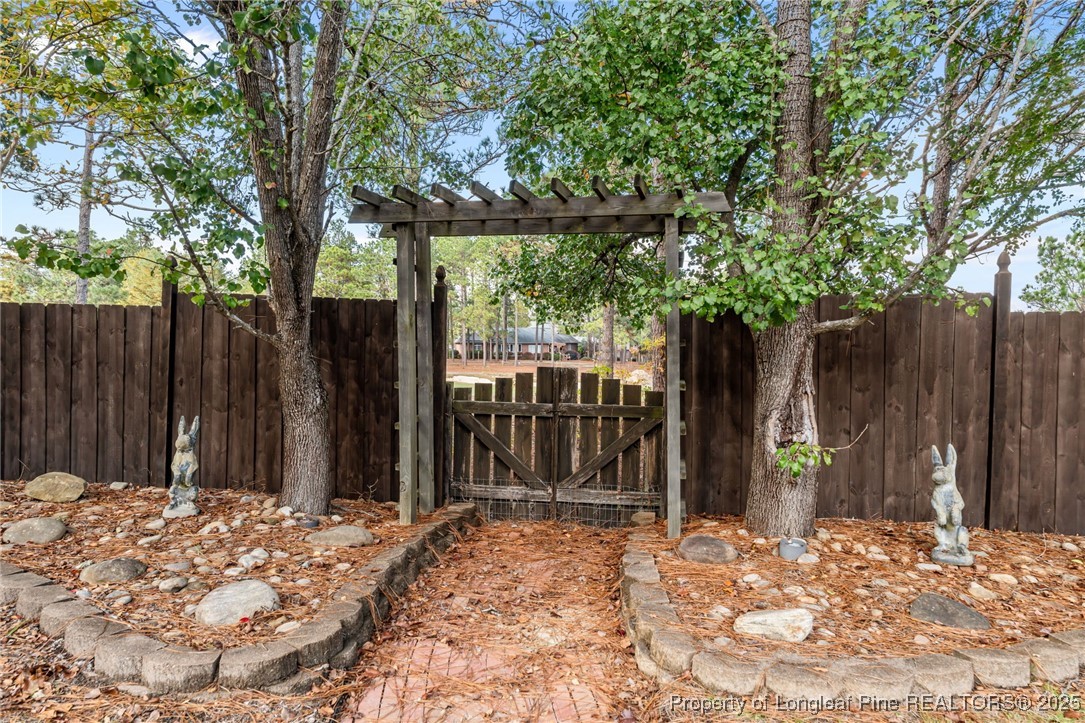 2000 Airport Road Whispering Pines, NC 28327 - Photo 12 of 50 a view of a backyard with large trees and wooden fence