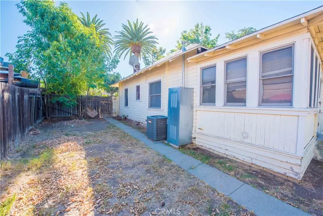 a backyard of a house with potted plants and large tree
