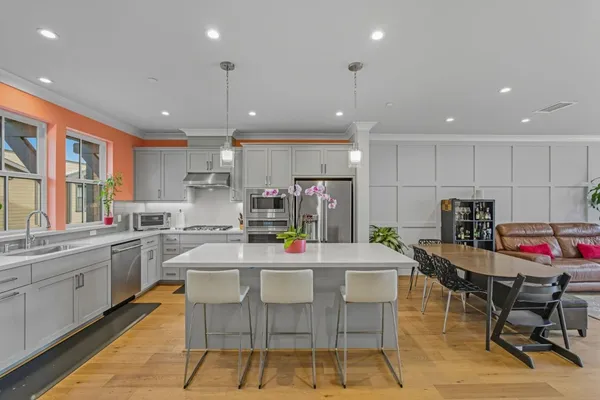 a kitchen with stainless steel appliances kitchen island granite countertop a dining table chairs sink and white cabinets