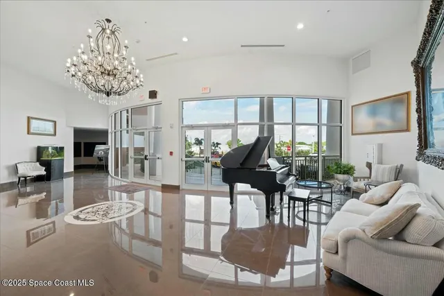 a living room with furniture a chandelier and a floor to ceiling window