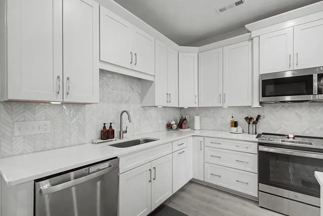 a kitchen with white cabinets and stainless steel appliances