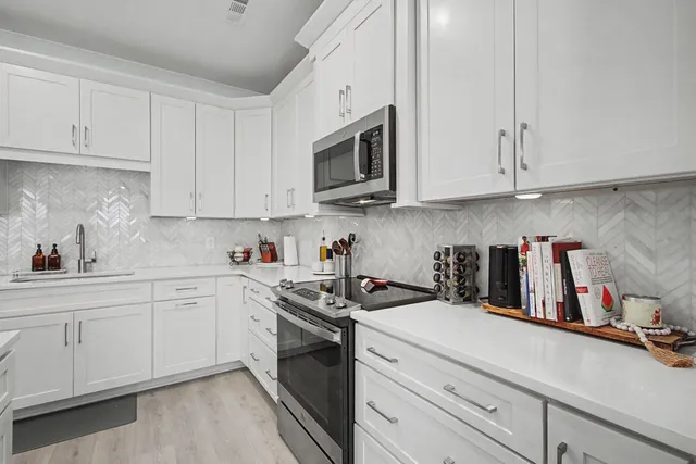 a kitchen with stainless steel appliances granite countertop a sink a stove and cabinets