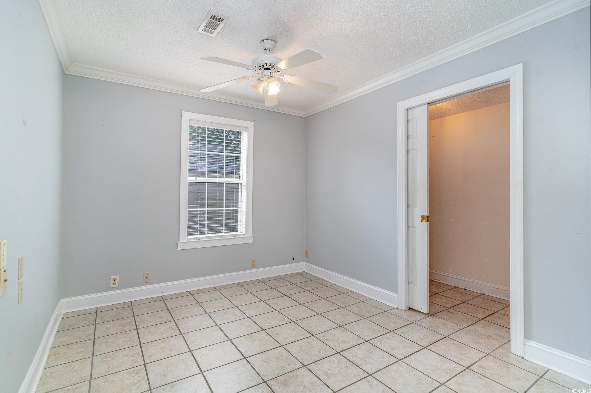 209 Kestrel Court Myrtle Beach, SC 29588 - Photo 4 of 27 Tiled empty room with ceiling fan and crown moldin