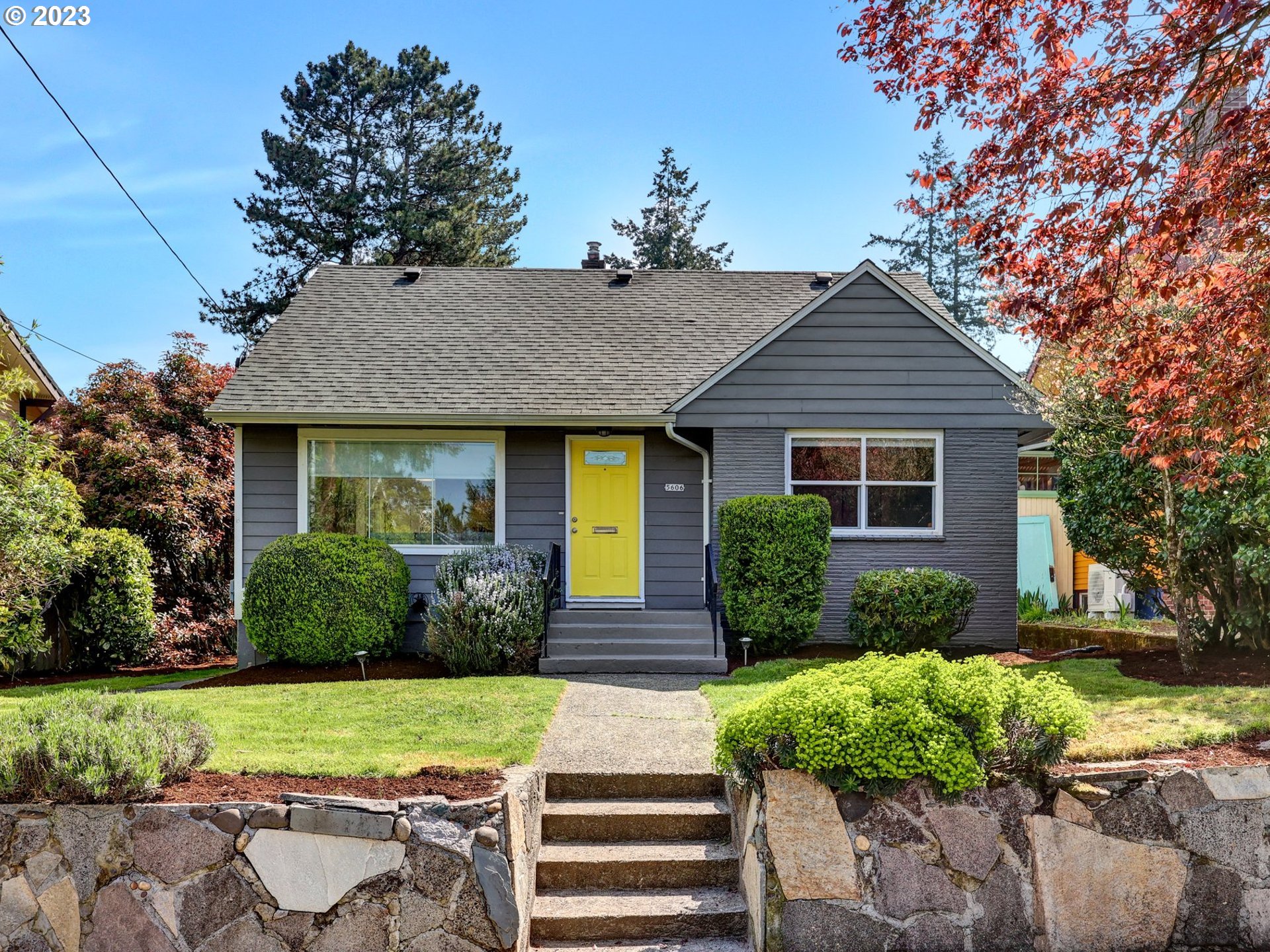 a front view of a house with a yard and potted plants