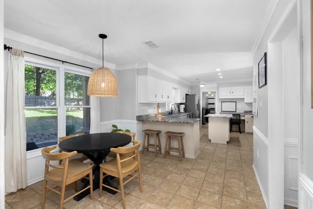 a kitchen with a dining table chairs and white cabinets