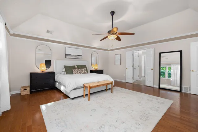 a bedroom with a bed ceiling fan and a wooden floor
