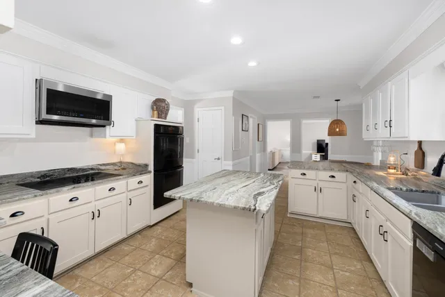 a large kitchen with granite countertop a sink and dishwasher stove top oven with wooden floor