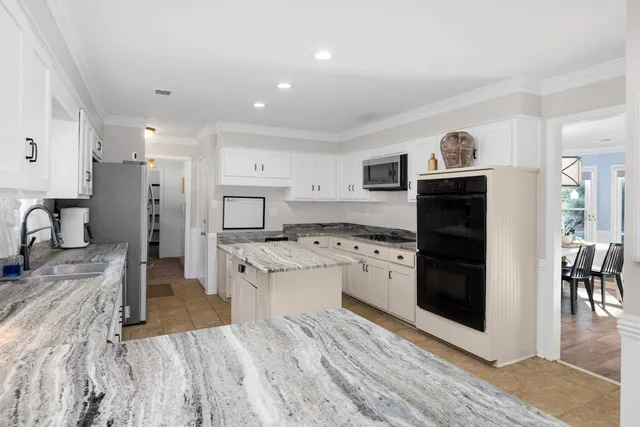 a kitchen with stainless steel appliances granite countertop a refrigerator a stove a sink a microwave and island