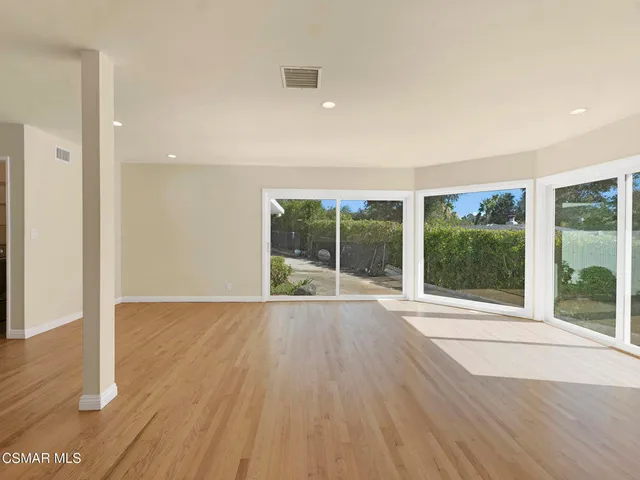 a living room with furniture and kitchen view with wooden floor