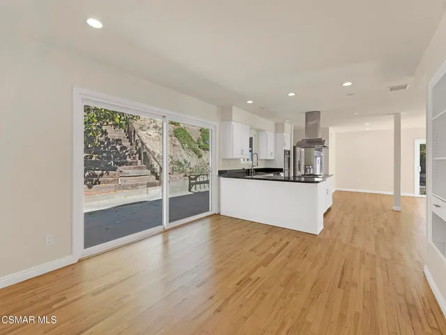 a view of an empty room with wooden floor and fan