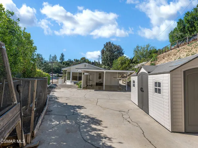 a view of patio with table and chairs under an umbrella with a small yard