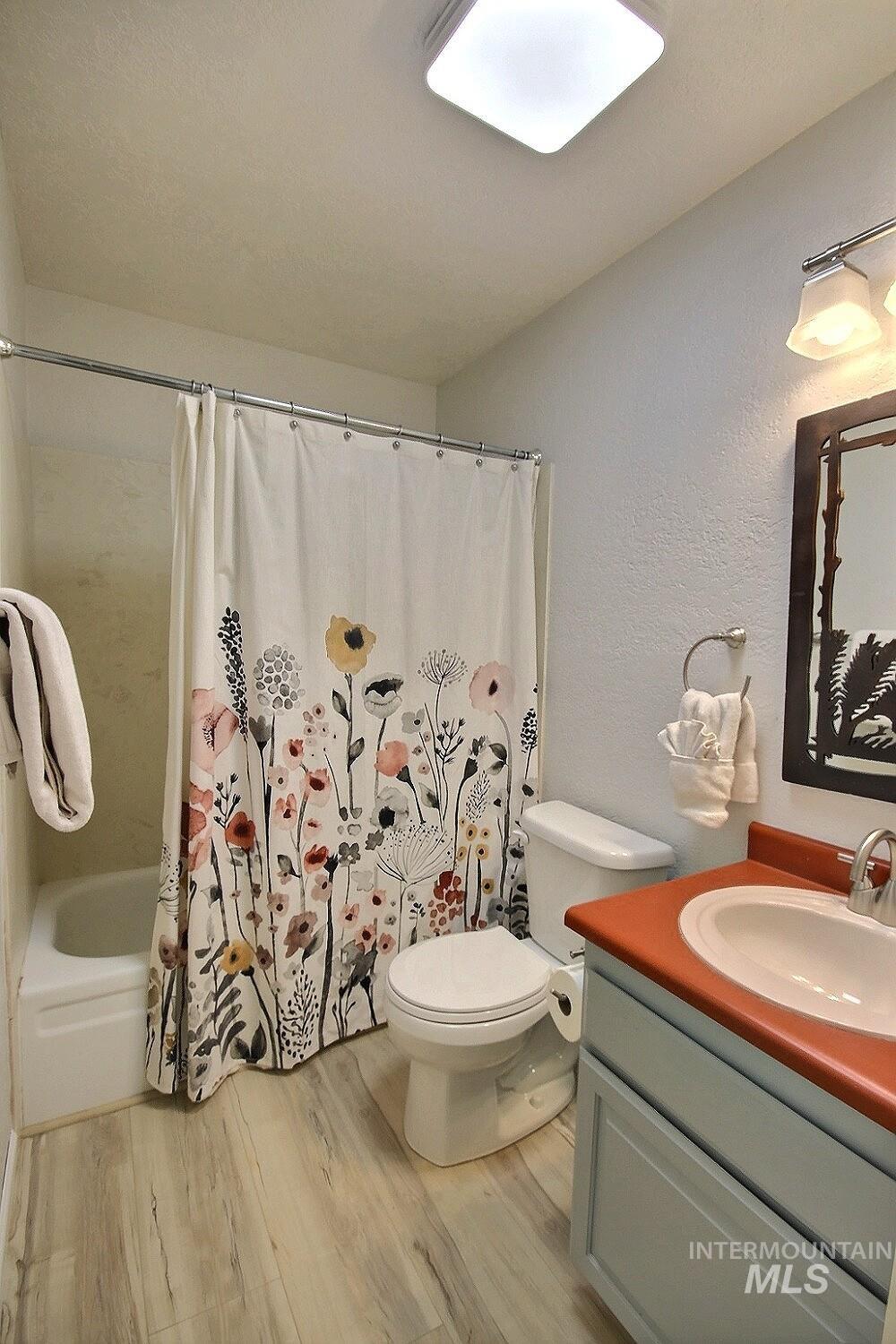 1640 Davis Avenue, Unit 7 McCall, ID 83638 - Photo 11 of 21 Bathroom featuring vanity, light wood-style floors, shower / tub combo with curtain, and a textured wall