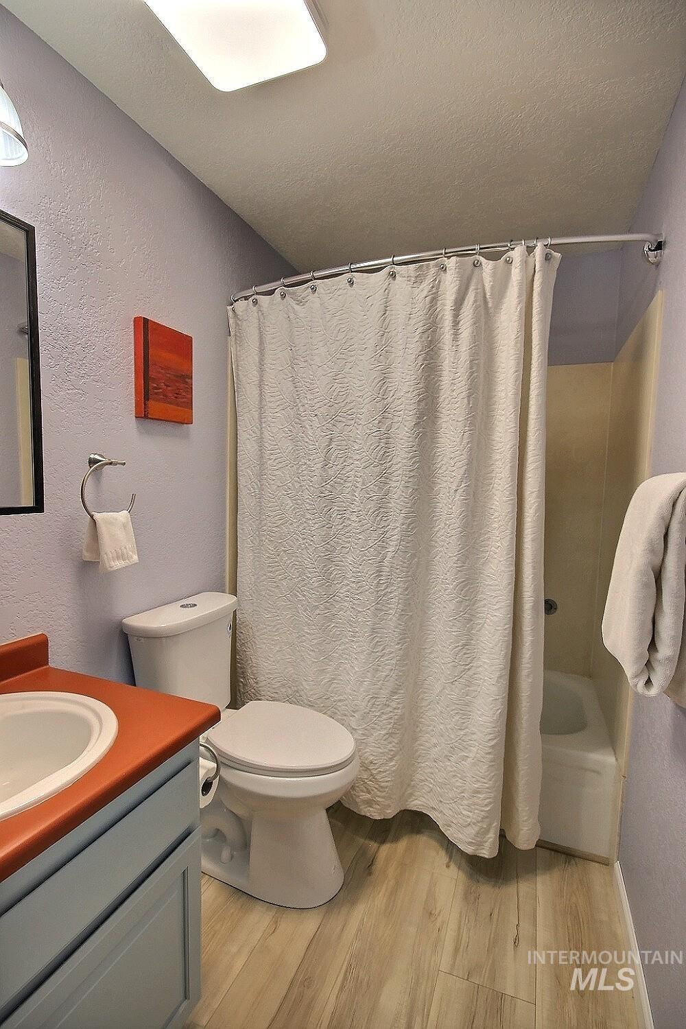 1640 Davis Avenue, Unit 7 McCall, ID 83638 - Photo 15 of 21 Bathroom featuring a textured wall, vanity, light wood-style floors, a textured ceiling, and shower / bath combo