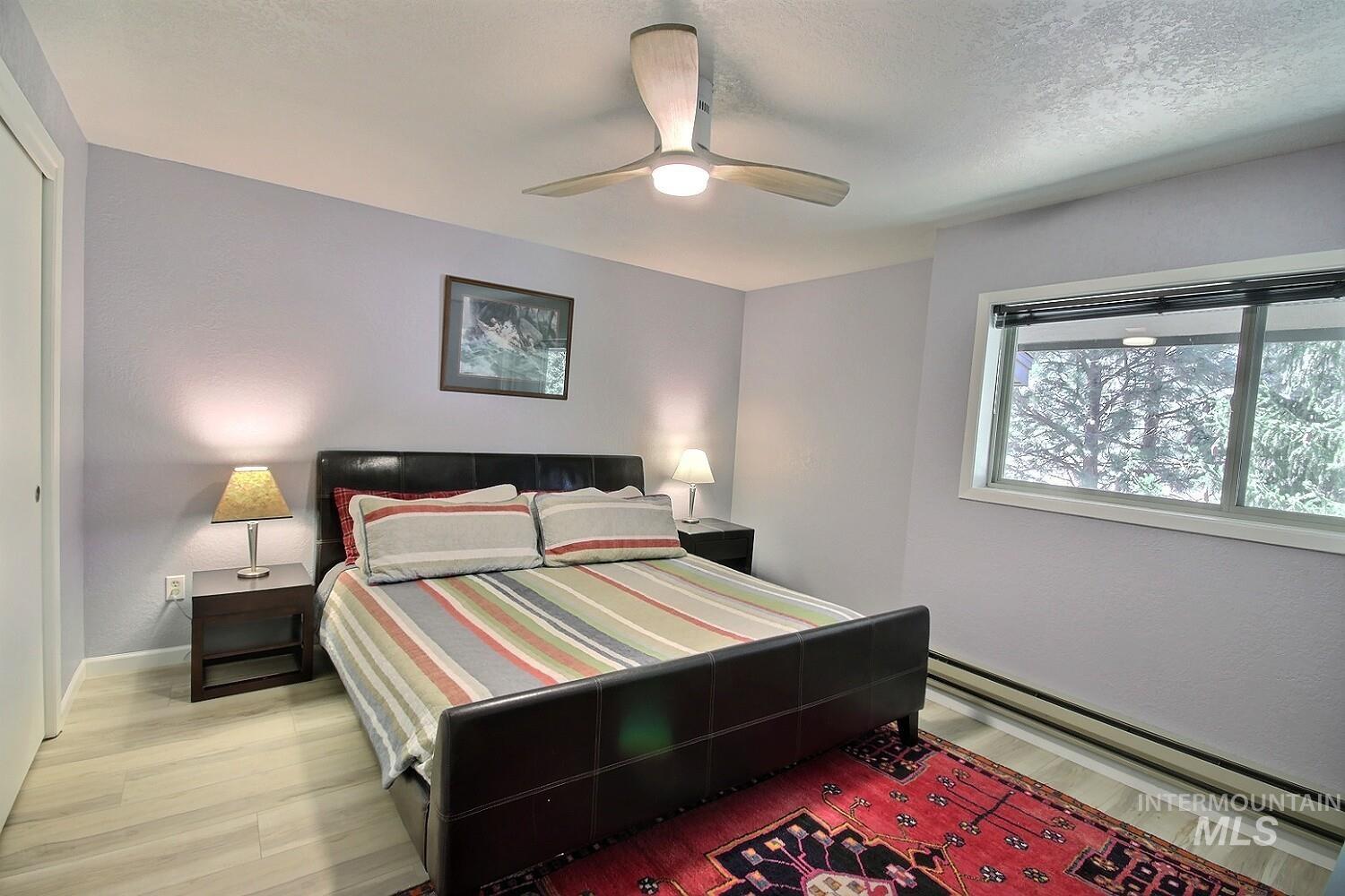 1640 Davis Avenue, Unit 7 McCall, ID 83638 - Photo 16 of 21 Bedroom featuring a baseboard heating unit, a ceiling fan, light wood-style floors, and a textured ceiling