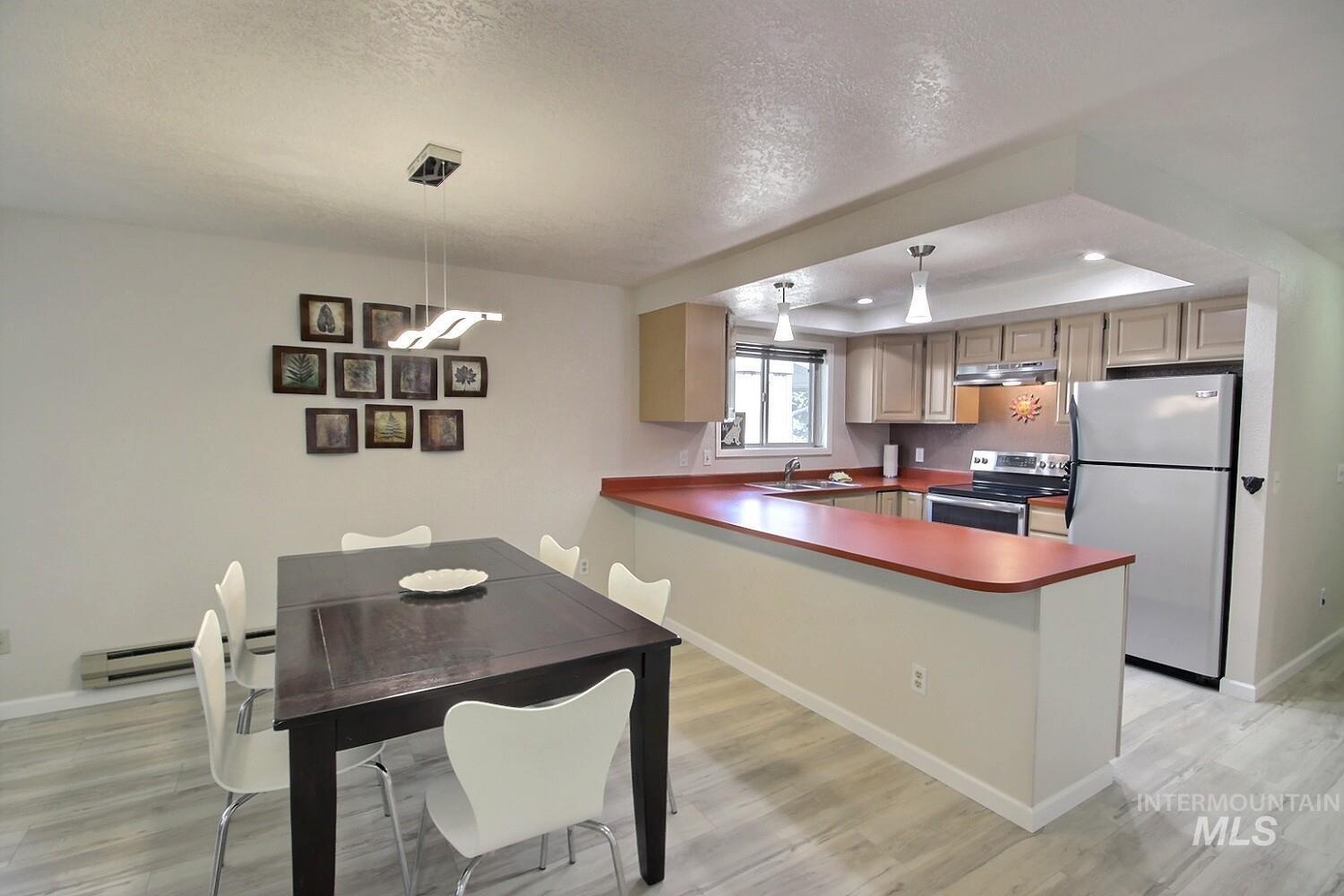 1640 Davis Avenue, Unit 7 McCall, ID 83638 - Photo 3 of 21 Kitchen with stainless steel appliances, dark countertops, a peninsula, a tray ceiling, and decorative light fixtures