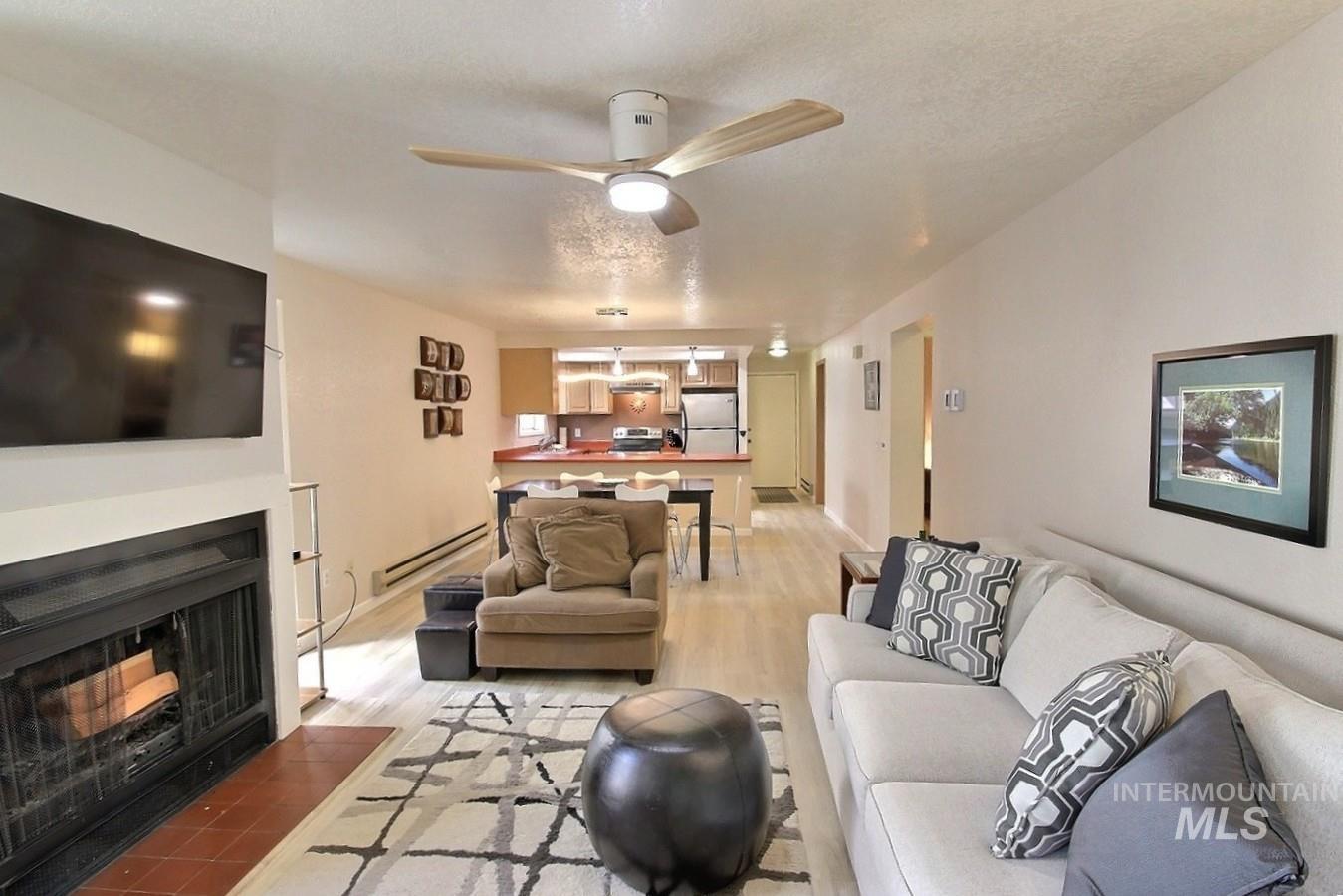 1640 Davis Avenue, Unit 7 McCall, ID 83638 - Photo 5 of 21 Living room with a fireplace with flush hearth, light wood-type flooring, a baseboard heating unit, ceiling fan, and a textured ceiling