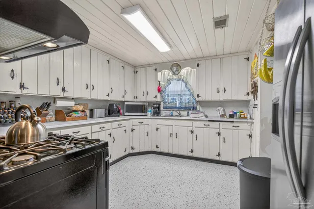 a kitchen with stainless steel appliances granite countertop a refrigerator sink and white cabinets