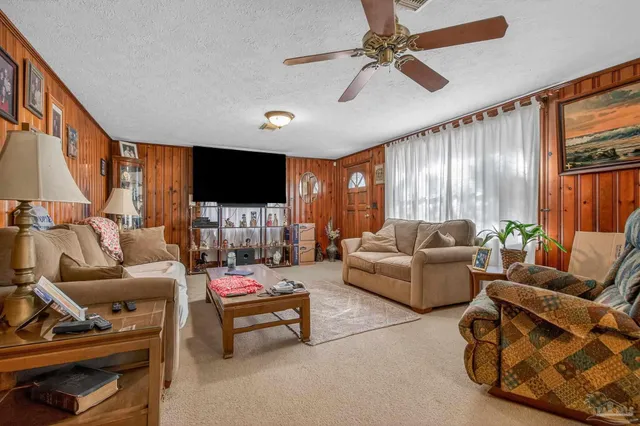 a living room with furniture a ceiling fan and a flat screen tv
