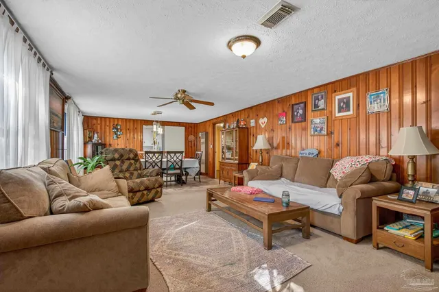 a living room with furniture ceiling fan and a large window