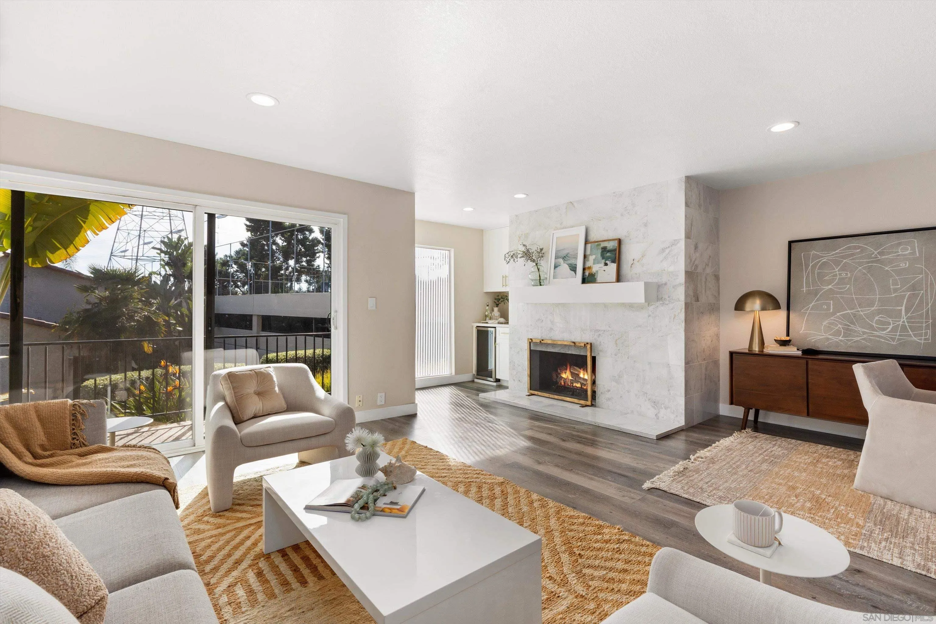 a living room with furniture a fireplace and a large window with balcony view